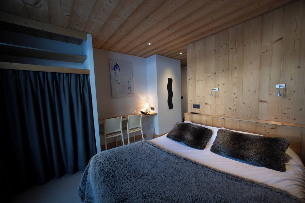 A bedroom with a bed, a desk, and a chair.