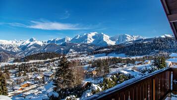 A snowy mountain landscape with a village and a wooden balcony.