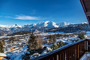 A snowy mountain landscape with a village and a wooden balcony.