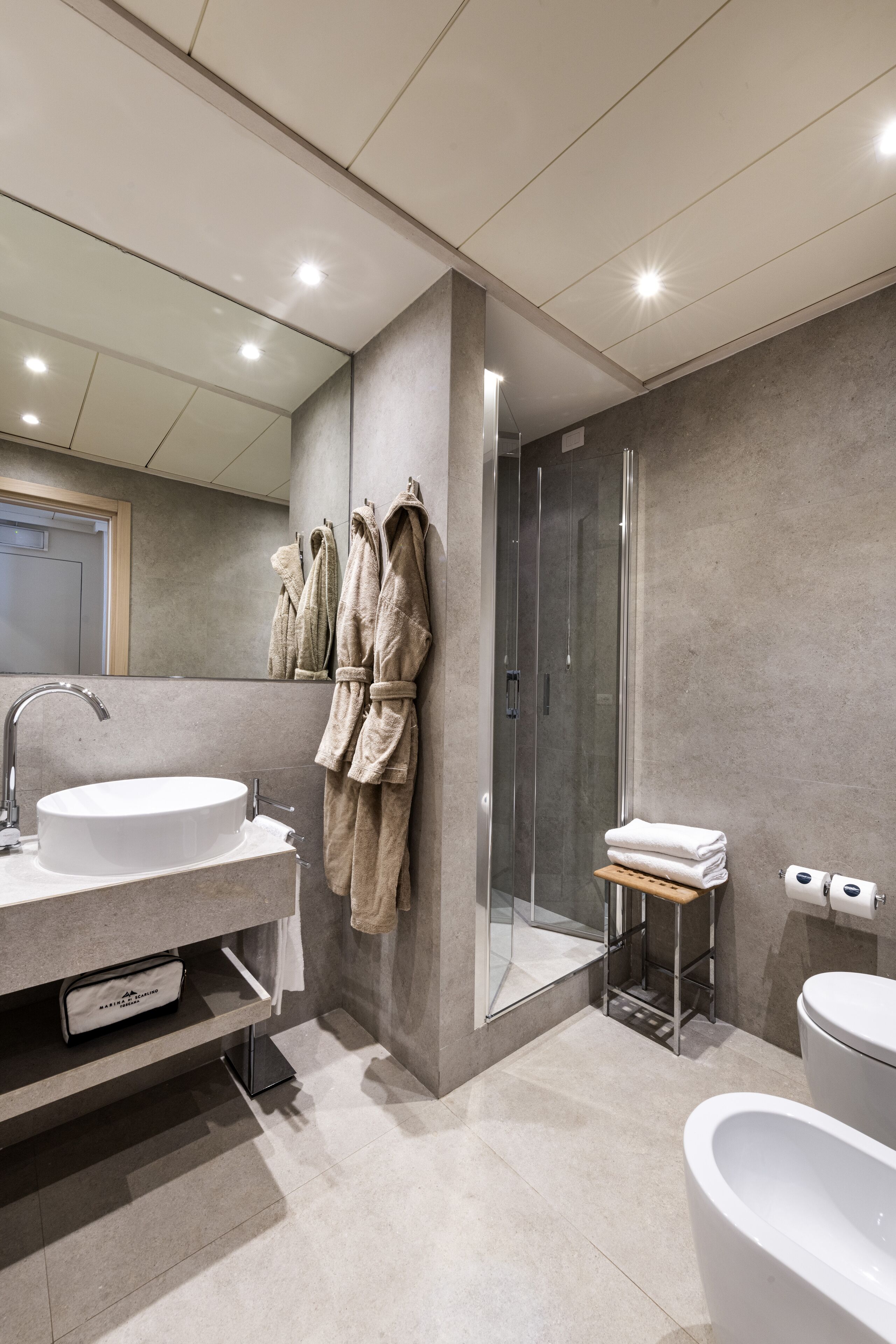 Un baño moderno con un lavamanos grande, cabina de ducha con vidrio y un inodoro.