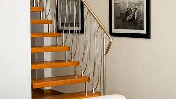 Una escalera de madera con barandilla de metal que conduce a un piso superior.