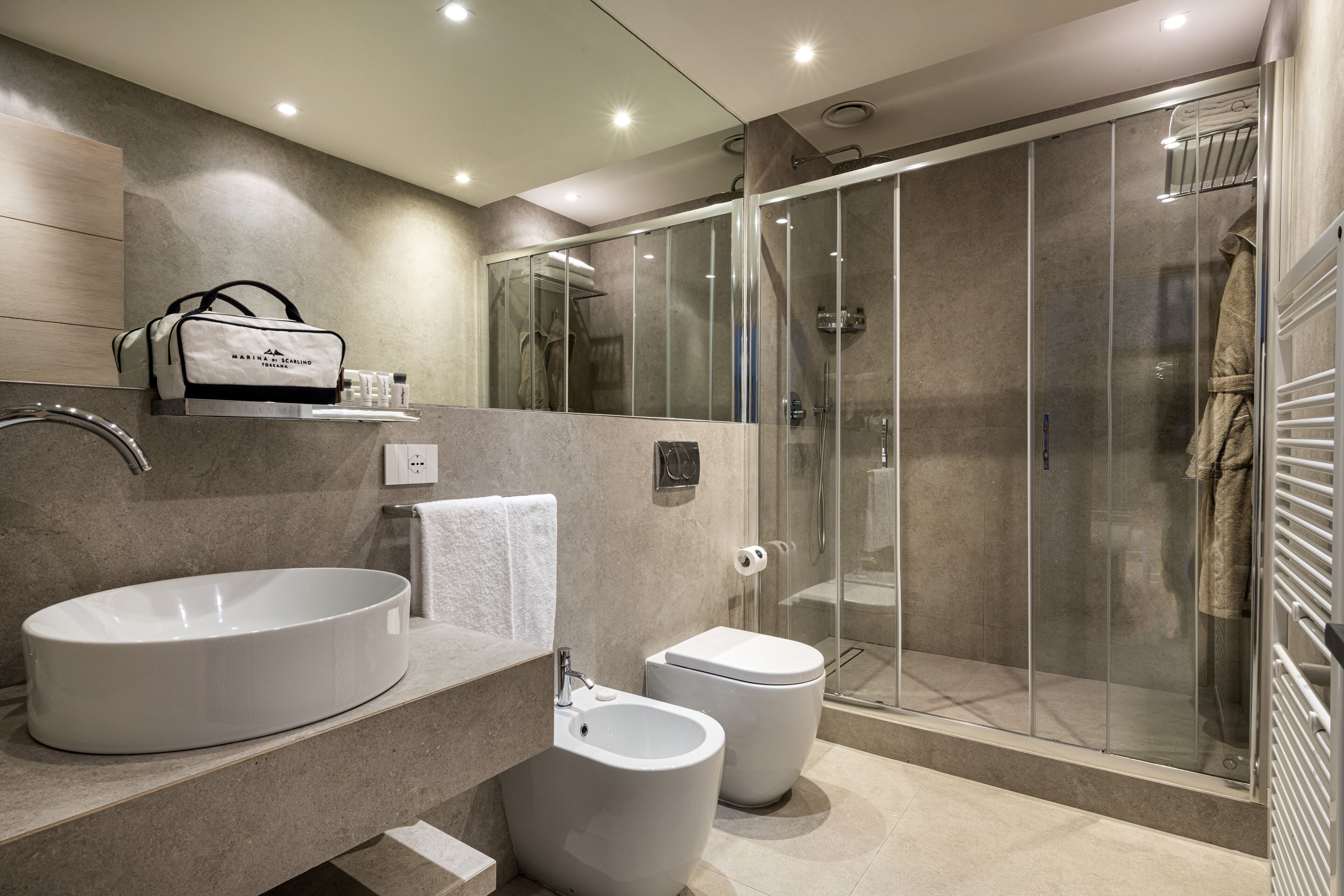 A modern bathroom with a large sink, bidet, toilet, and a glass-enclosed shower area.