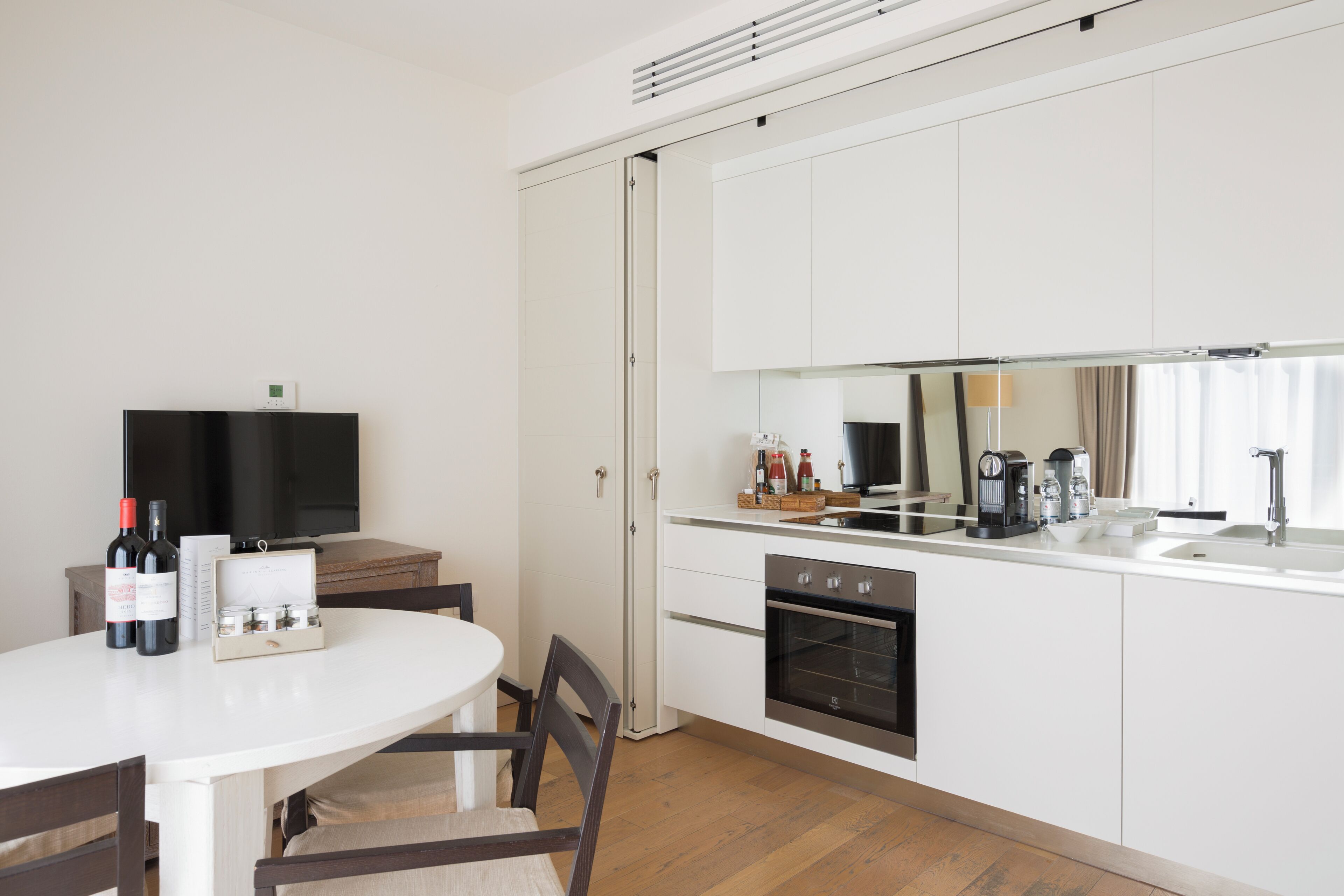 A modern kitchen with white cabinets, a built-in oven, and a large window.