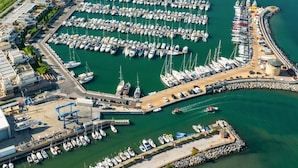 Vista aérea de un puerto deportivo con numerosas embarcaciones amarradas, rodeado de vegetación y colinas.