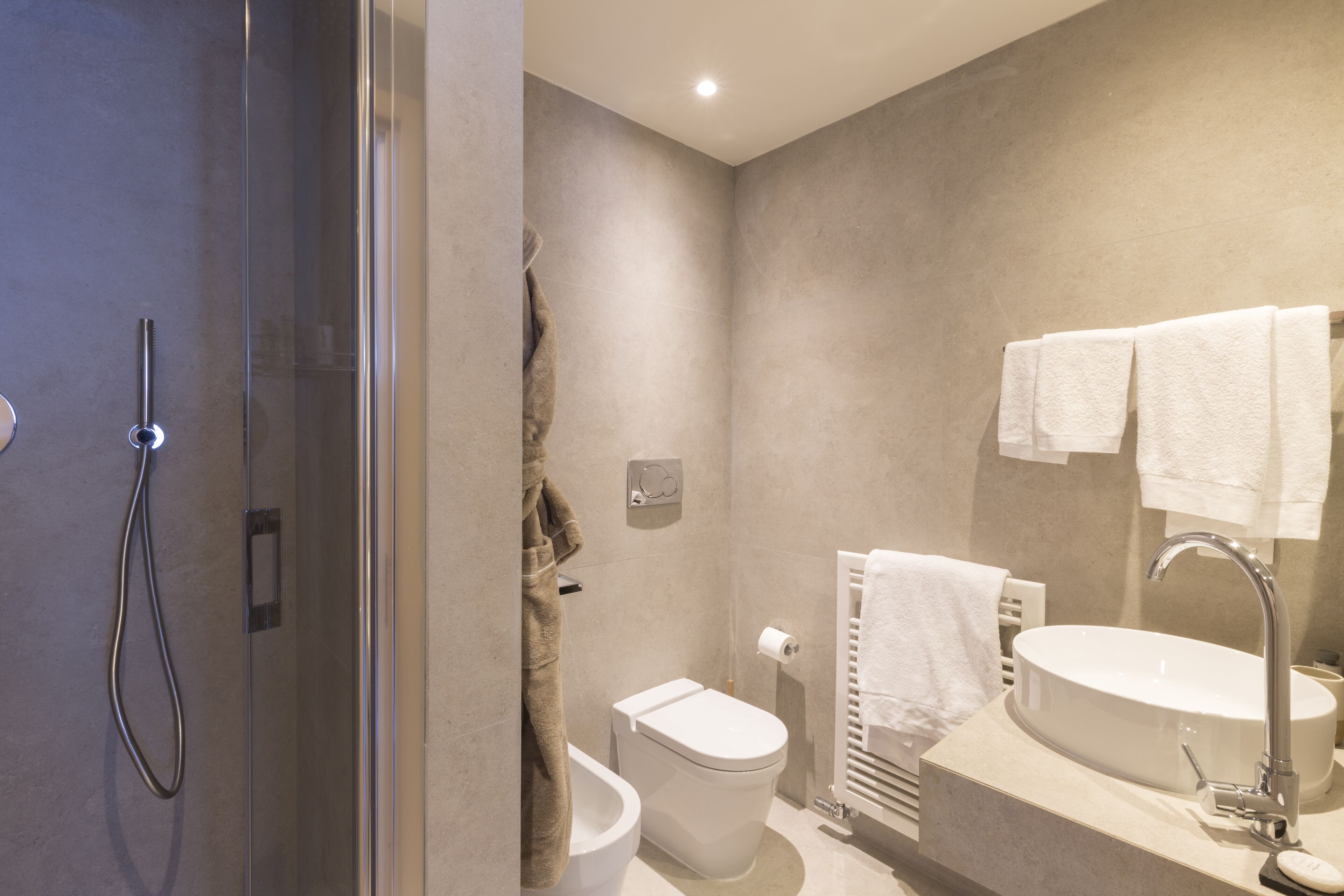 A modern bathroom with a glass shower enclosure, a toilet, a bidet, and a sink with a mirror.