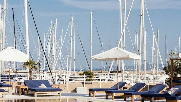 Una marina con varios barcos, sillas de descanso y sombrillas.