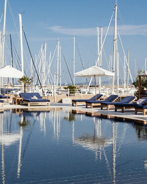 Una marina con varios barcos, sillas de descanso y sombrillas.