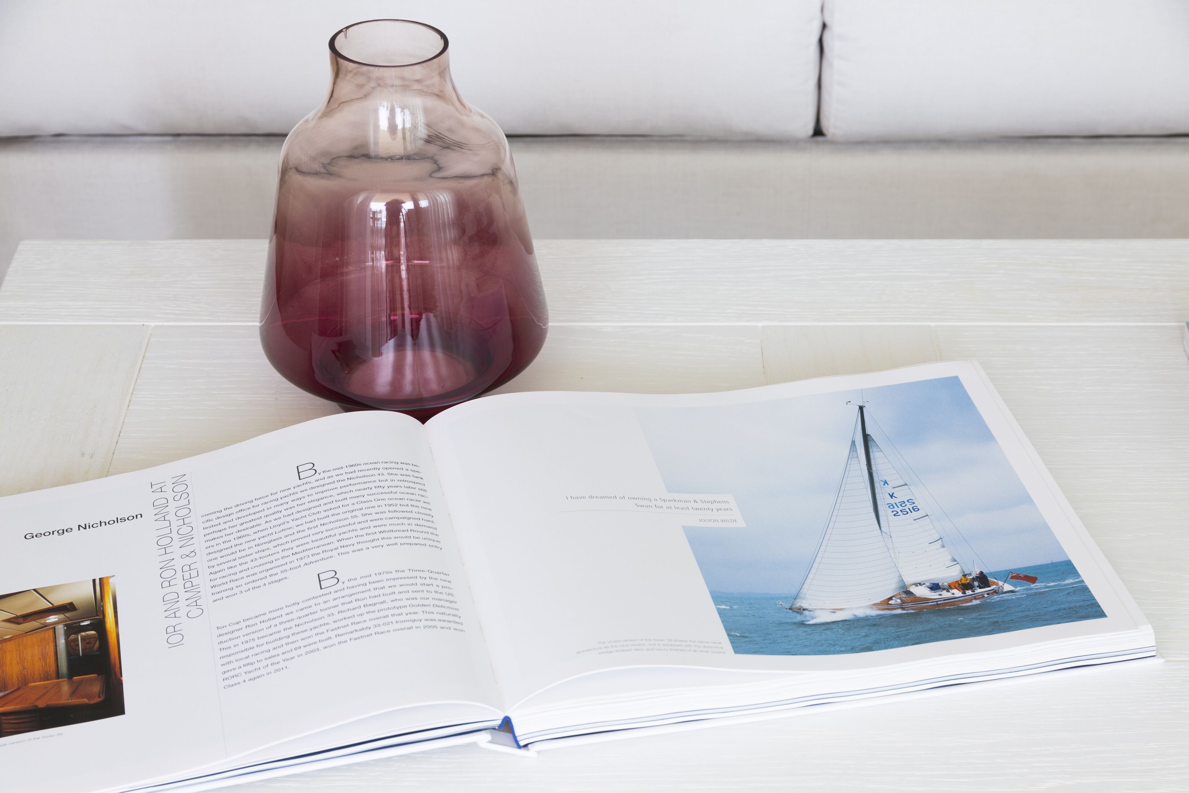 A book open to a page with text and a photograph of a sailboat on the water.