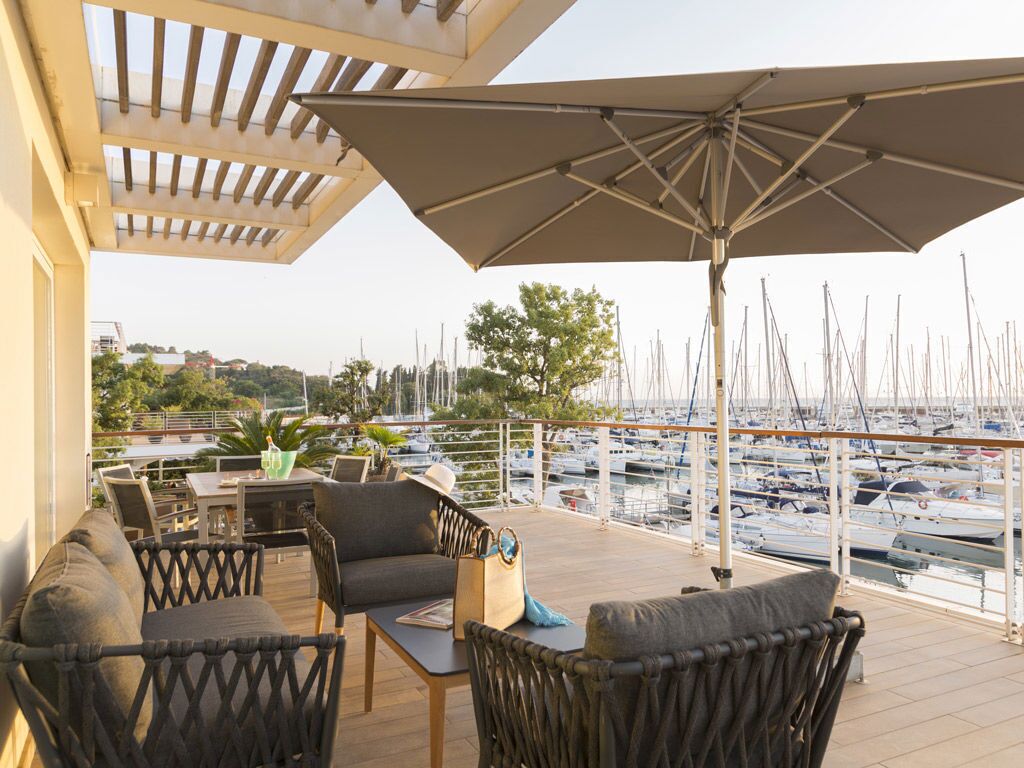 Un espace extérieur abrité, aménagé avec des meubles en osier, une table et un grand parasol.