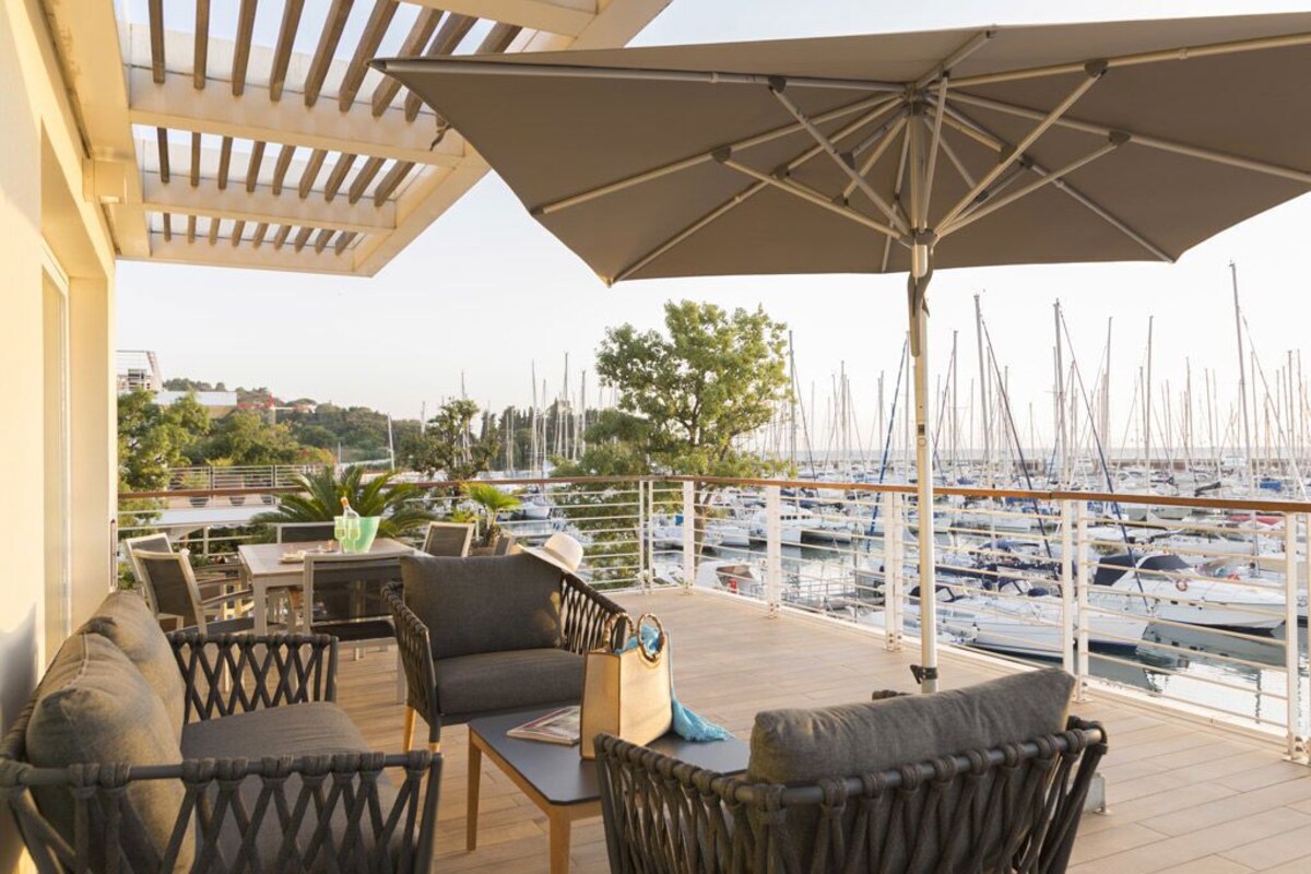 A covered outdoor seating area with wicker furniture, a table, and a large umbrella.