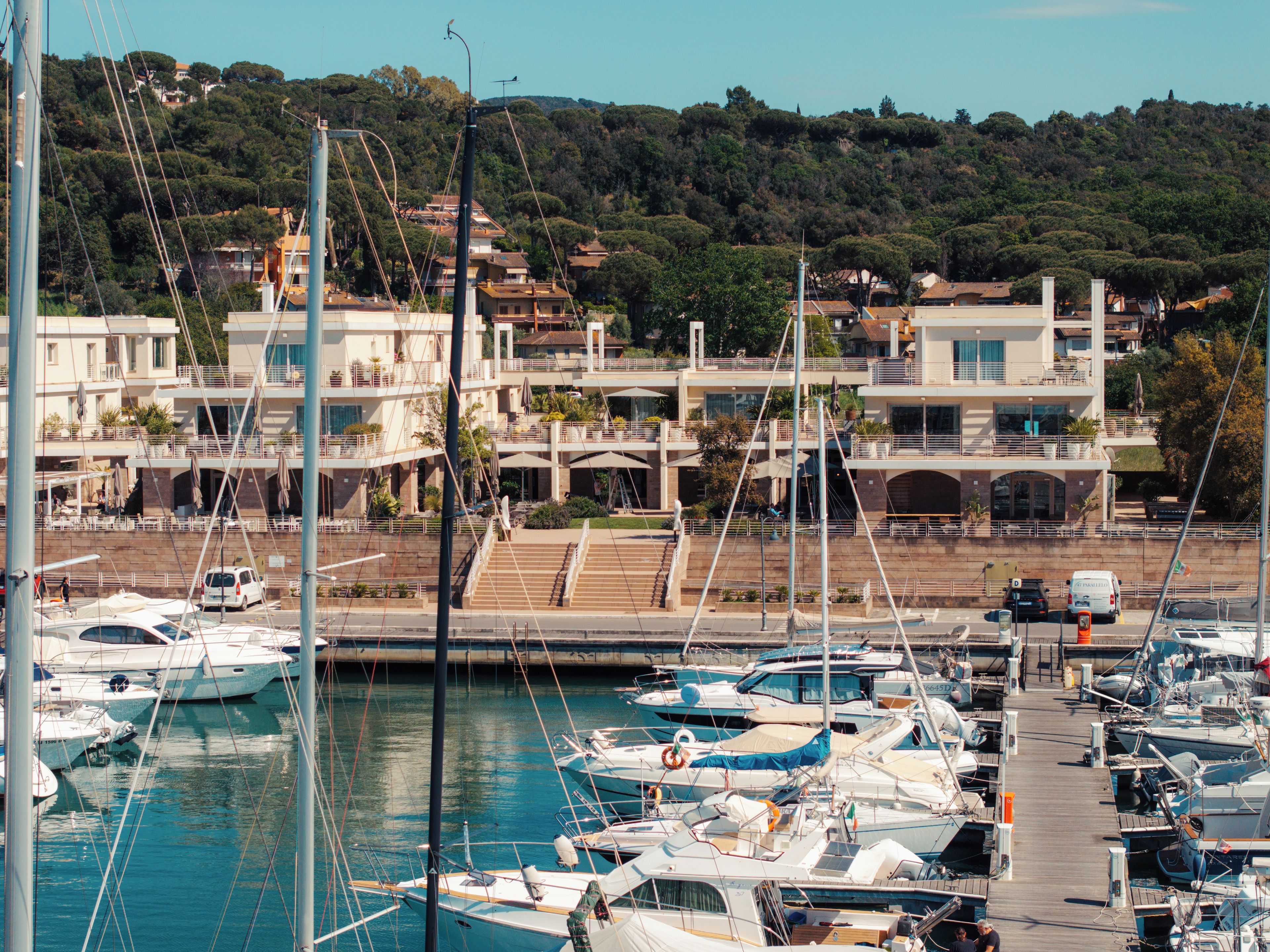 Un puerto deportivo con barcos amarrados, un puente peatonal y edificios al fondo.