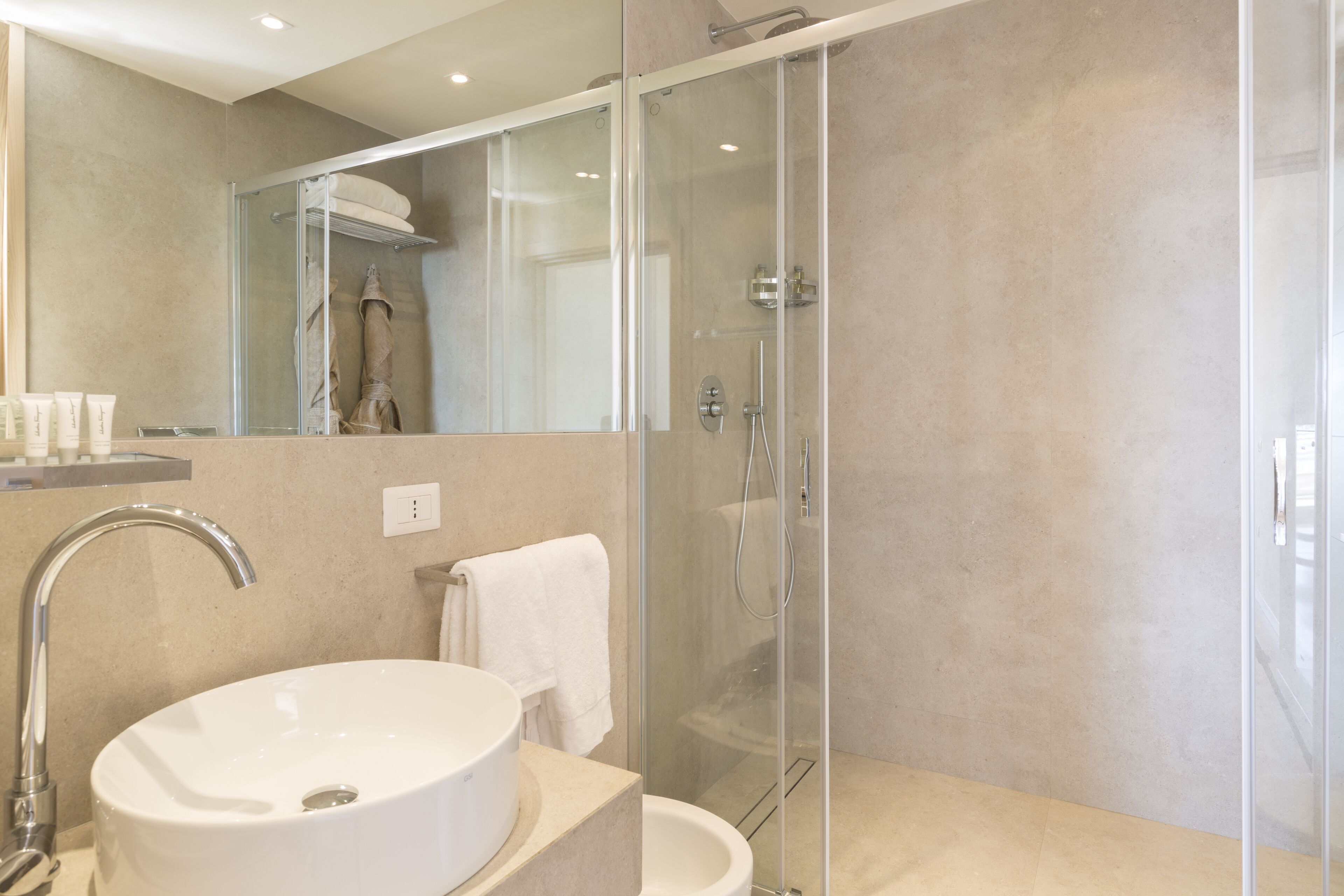 A modern bathroom with a glass-enclosed shower, a white sink, and a towel hanging on the wall.