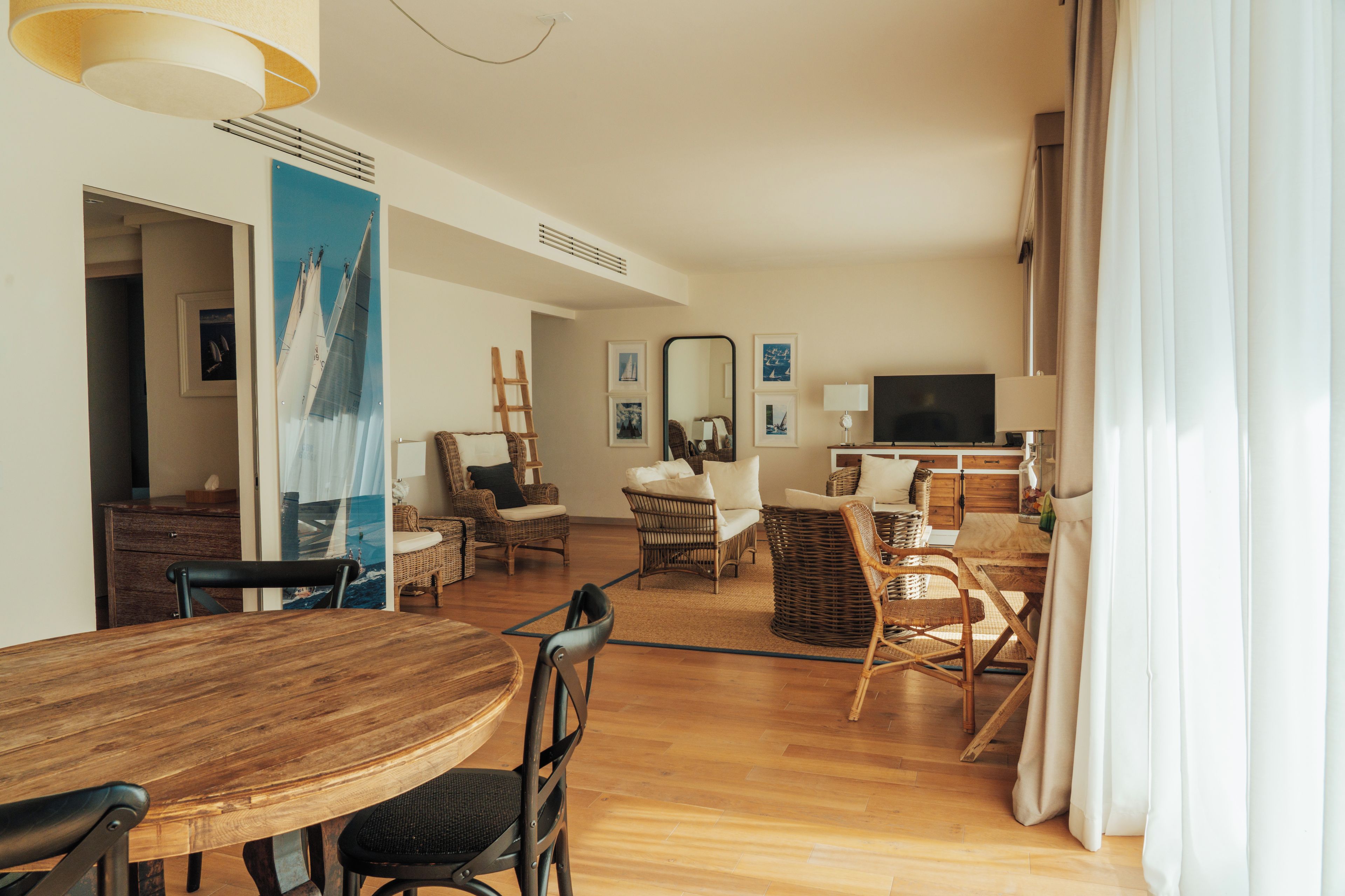 Un salón amplio con una mesa de comedor de madera, muebles de mimbre y un televisor.