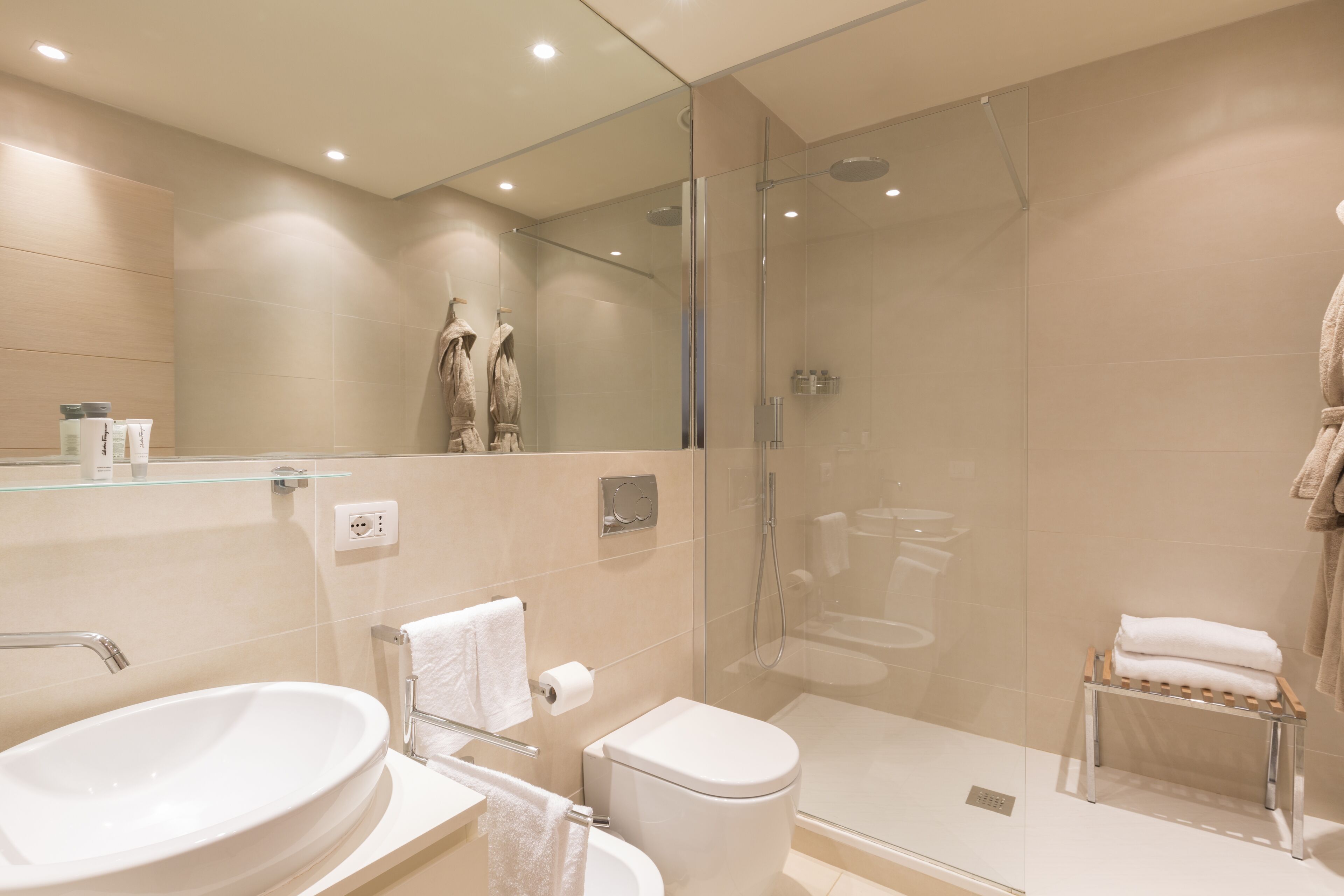 A modern bathroom with a glass-enclosed shower, a white sink, and a toilet.