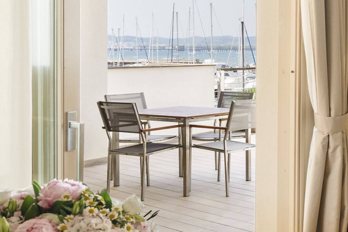 A balcony with a table and chairs, a flower arrangement, and a view of the marina.