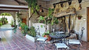 An outdoor patio with stone walls, a glass table, and metal chairs. - Os Areeiros (Vilaboa)