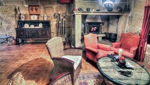 A cozy living room with a stone fireplace, wicker furniture, and a red armchair. - Os Areeiros (Vilaboa)