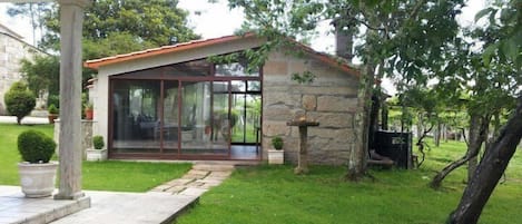 A modern house with a glass conservatory, stone walls, and a well-maintained lawn.