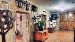 A rustic interior with stone walls, a fireplace, and a wooden door. - Os Areeiros (Vilaboa)
