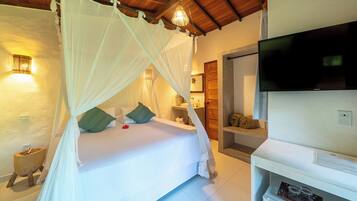 A bedroom with a bed under a canopy, a television, and a small wooden side table.