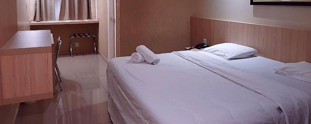 A hotel room with a bed, a desk, and a chair.