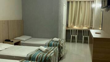 Habitación de hotel con dos camas individuales, un escritorio pequeño y una silla.