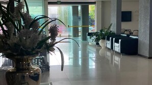 A spacious lobby with a reflective floor, a large vase with flowers, and seating areas. - Biss Inn (Goiania)