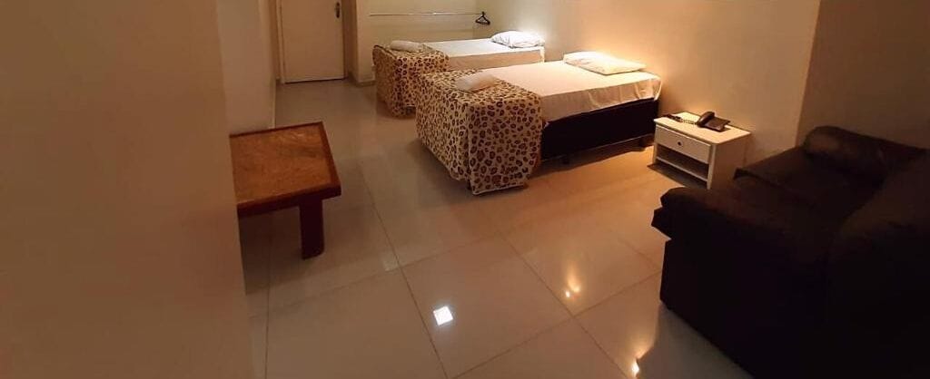 Una habitación con una cama, un sofá, una mesita y una mesita de noche con una lámpara.