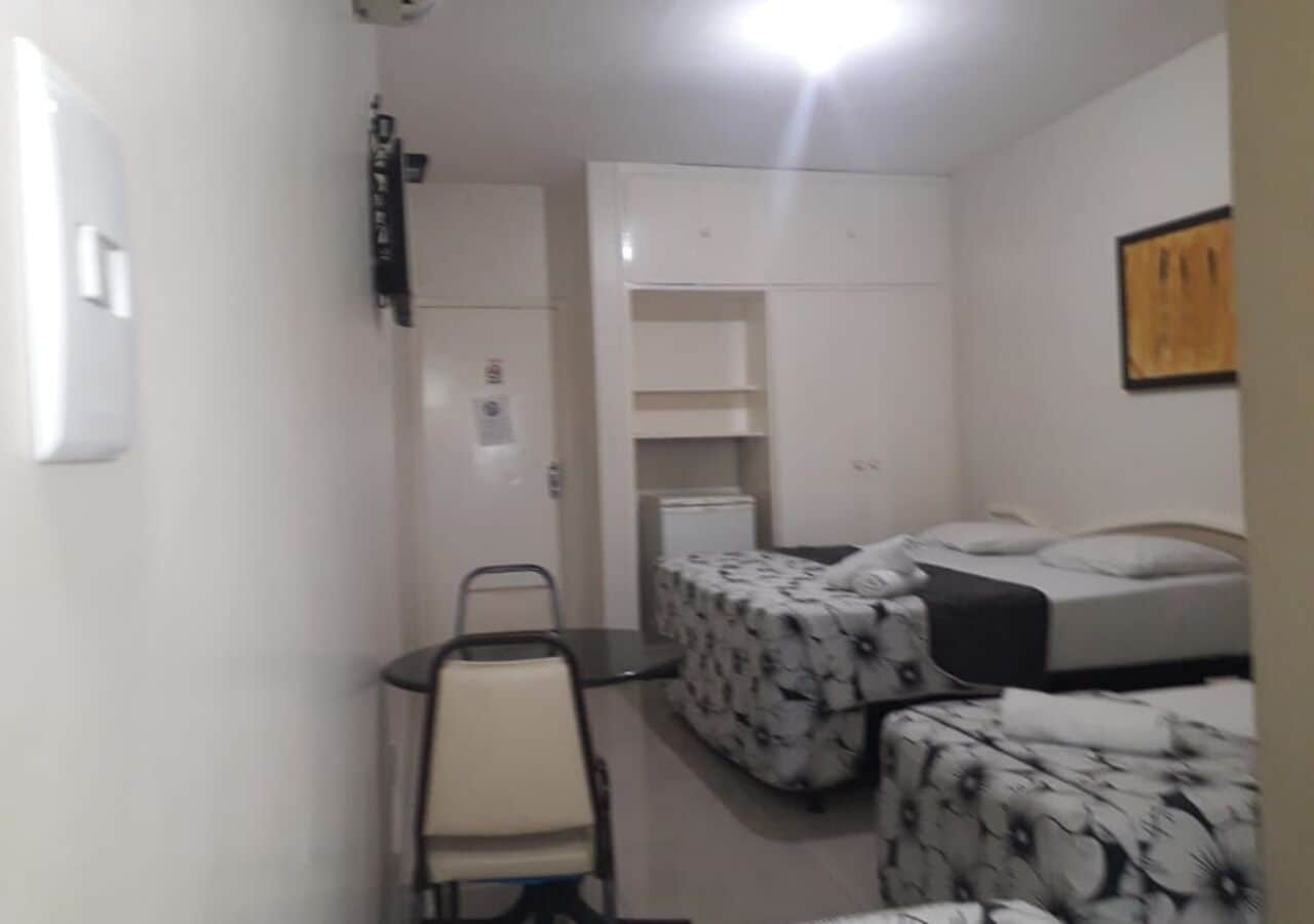 A small, compact room with two single beds, a desk, and a chair.