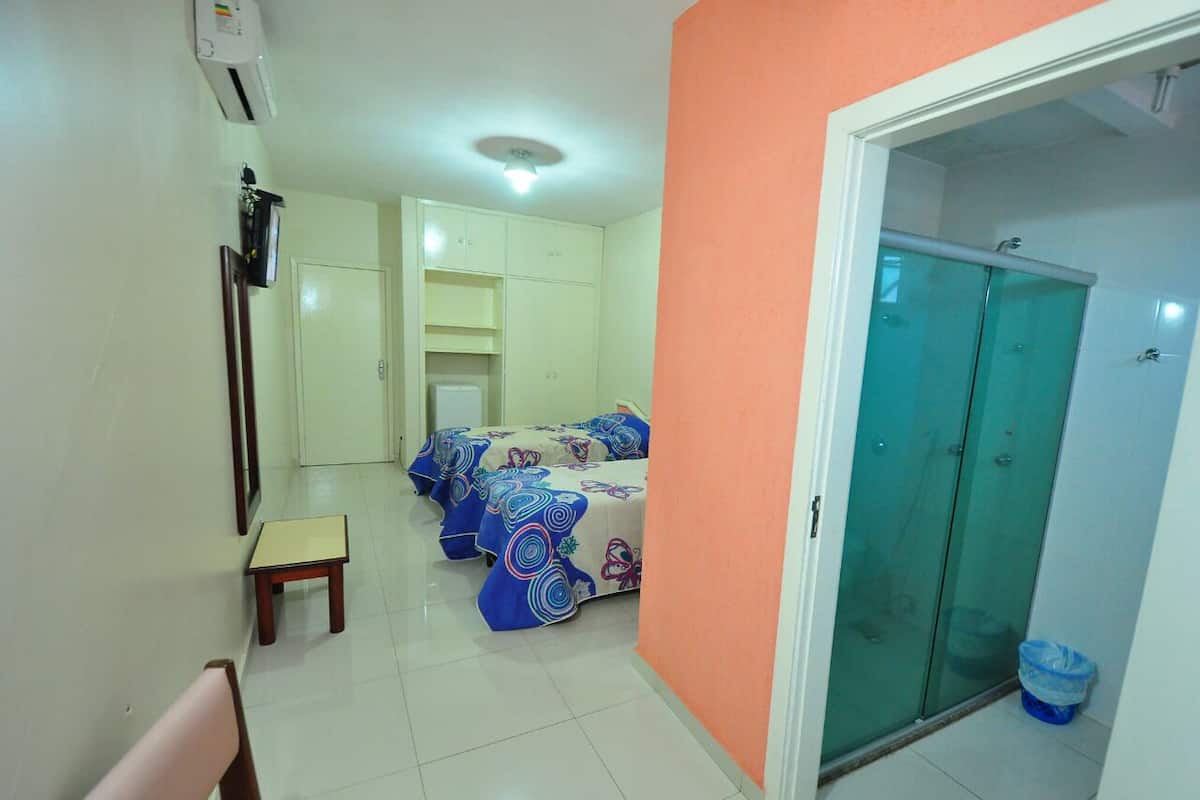 A hotel room with a bed, a small table, a chair, and a wardrobe.