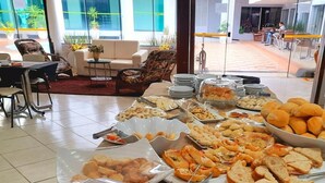 A buffet with various food items including bread, pastries, and meats. - Biss Inn (Goiania)