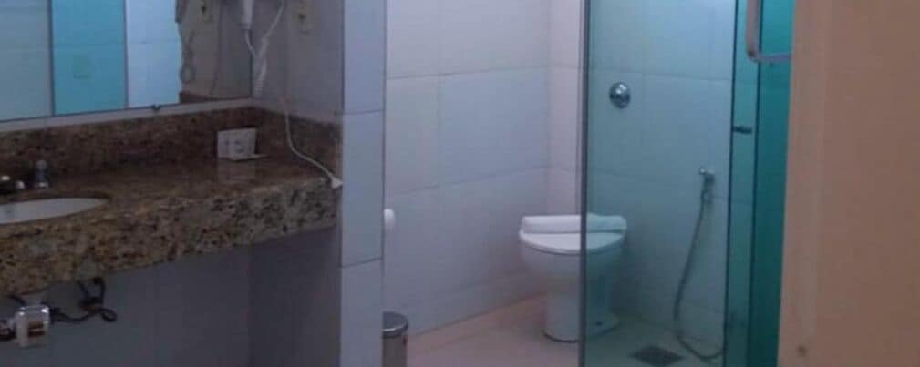 Un bany amb una pica de superfície de granat, un vàter blanc i una zona de banyera amb envàs de vidre.
