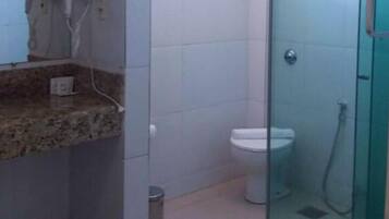 Un bany amb una pica de superfície de granat, un vàter blanc i una zona de banyera amb envàs de vidre.