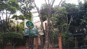 A hotel entrance with a green sign, brick walls, and a metal gate. - Hostal San Fernando (Cali)