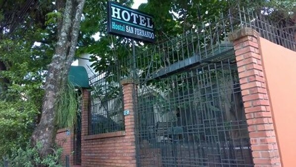 A hotel sign with a metal gate and brick pillars.