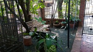 A garden area with a wooden bench, potted plants, and a metal fence. - Hostal San Fernando (Cali)