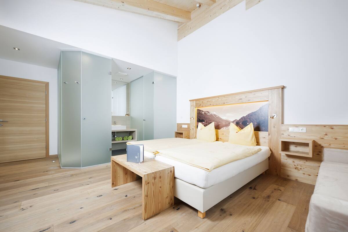 A modern bedroom with a wooden ceiling, a bed with a wooden headboard, a bedside table, and a nightstand.