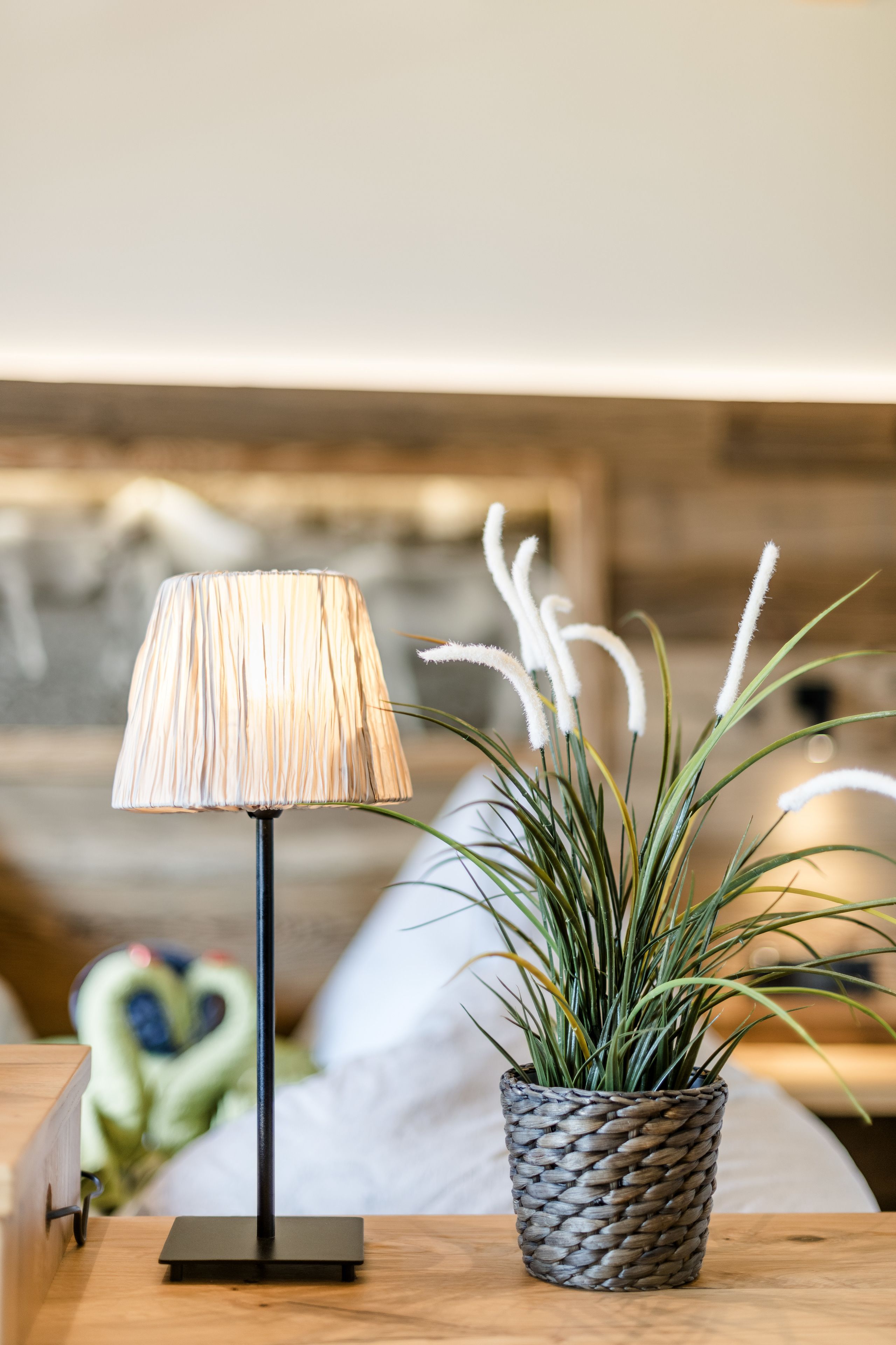 A bedside table with a lamp and a potted plant.
