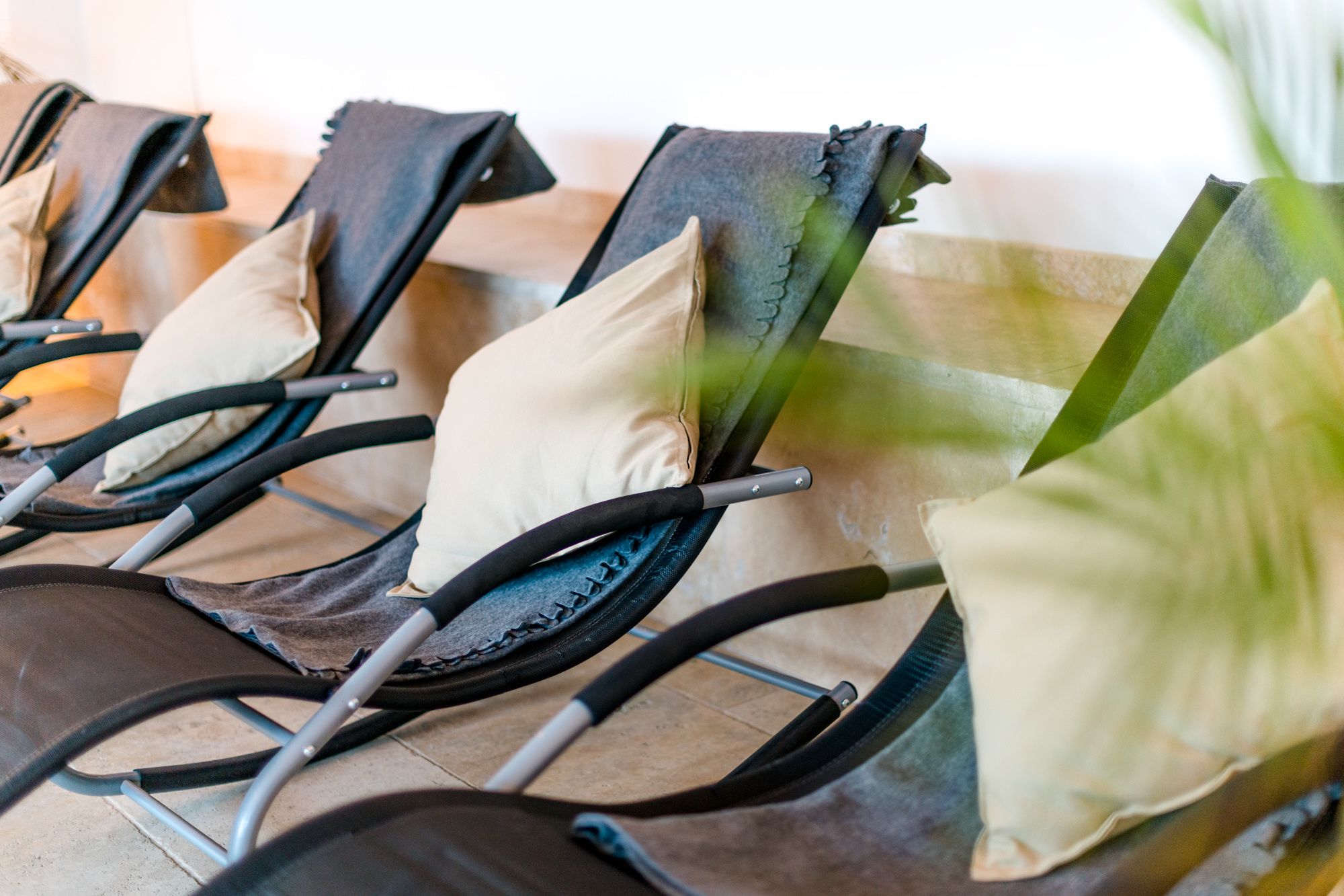 A row of chairs with black frames and beige cushions, arranged in a row.
