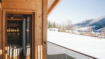 Una terraza de madera con barandilla de vidrio que da a un paisaje nevado.