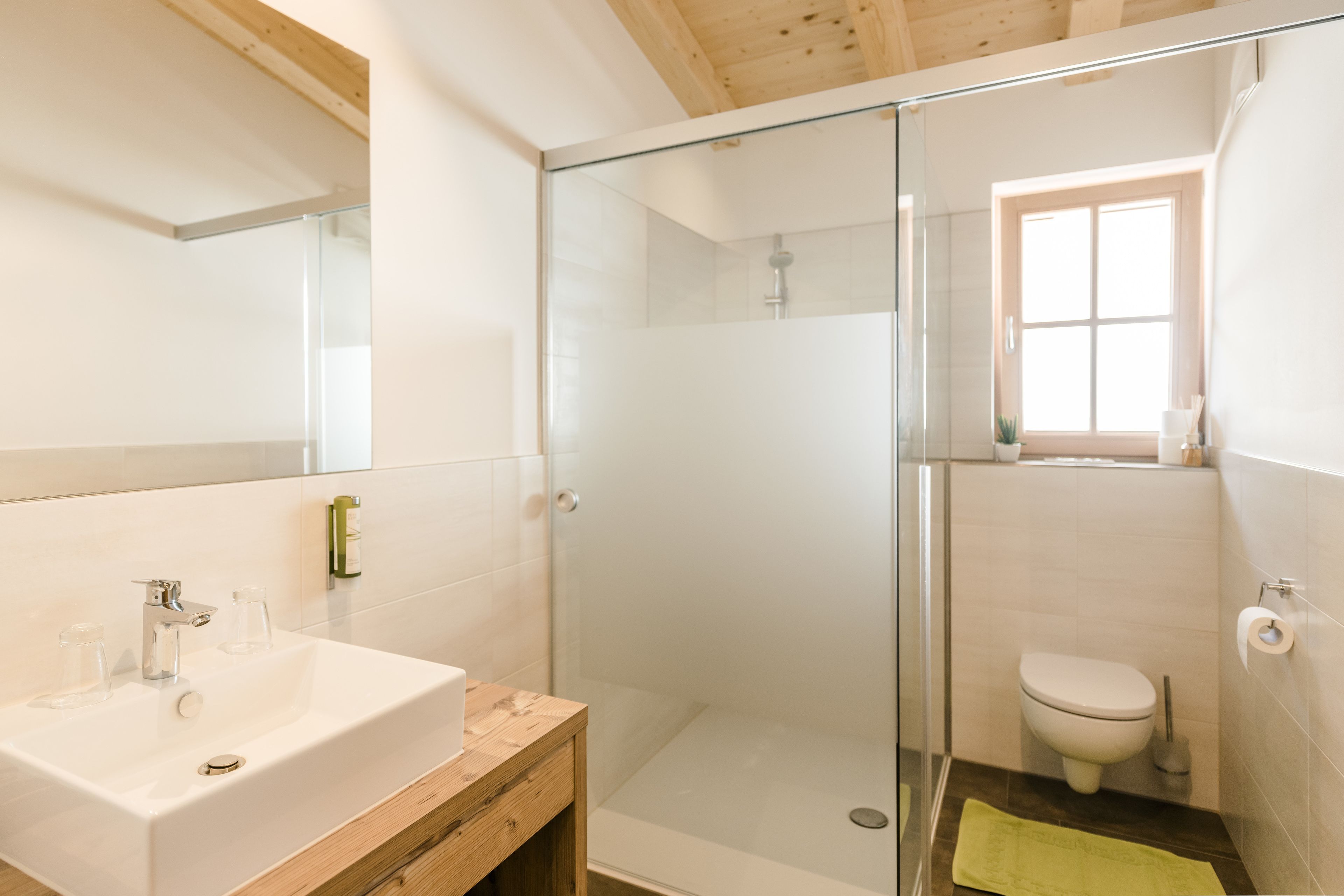 A modern bathroom with a glass-enclosed shower, a sink with a wooden vanity, and a toilet.