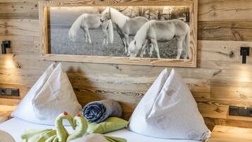 Pared de madera con fotografía en blanco y negro de un caballo enmarcado. Hay dos almohadas blancas y una toalla verde sobre una cama.