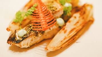 A plate of food with a fish, vegetables, and a decorative element.