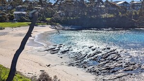 A staircase leading to a beach with a rocky shoreline and houses in the background.