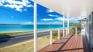 A wooden deck with a view of a coastal road and ocean.
