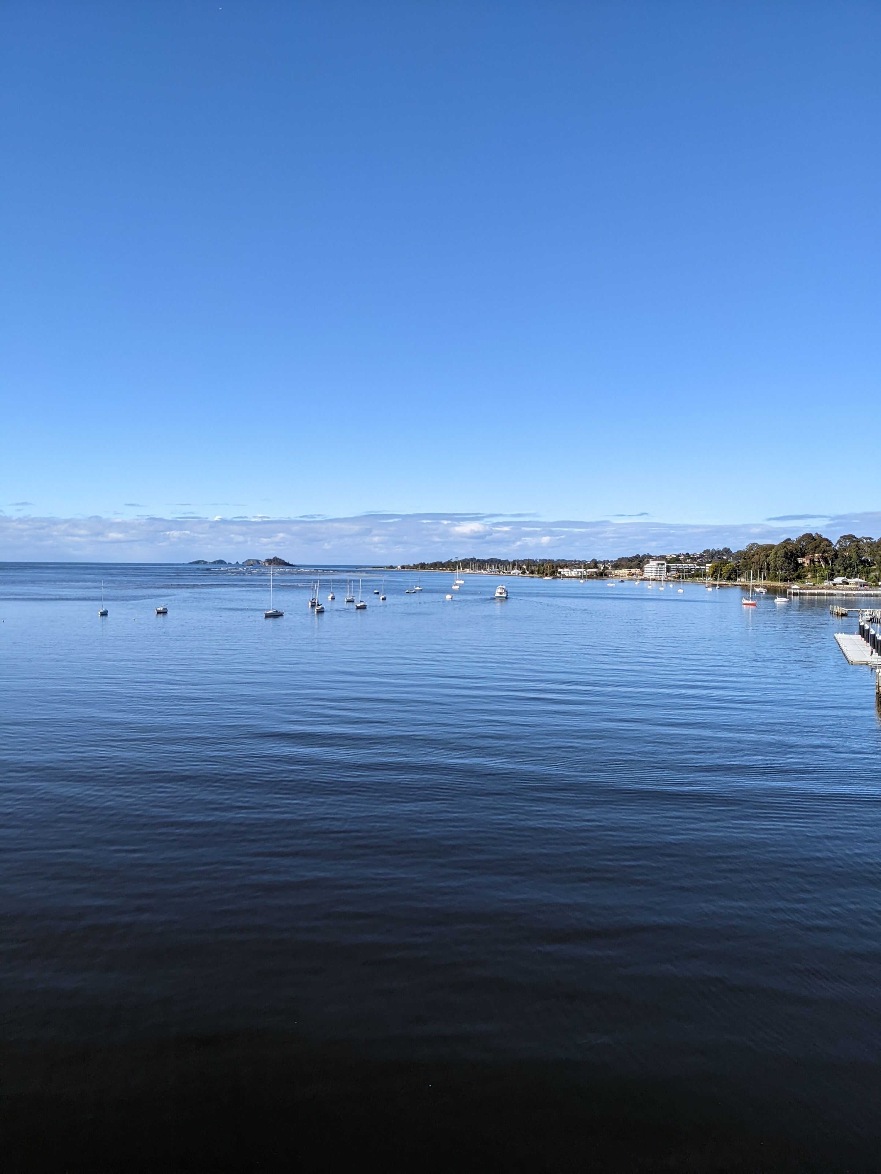 A calm waterfront with boats and a pier.