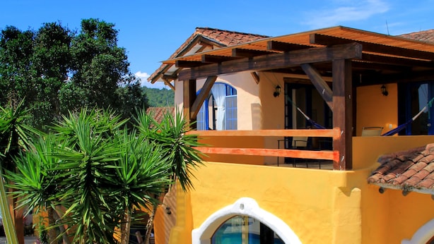 Un bâtiment à deux étages, doté d’une façade jaune, d’un balcon en bois et de fenêtres en arc de cercle.
