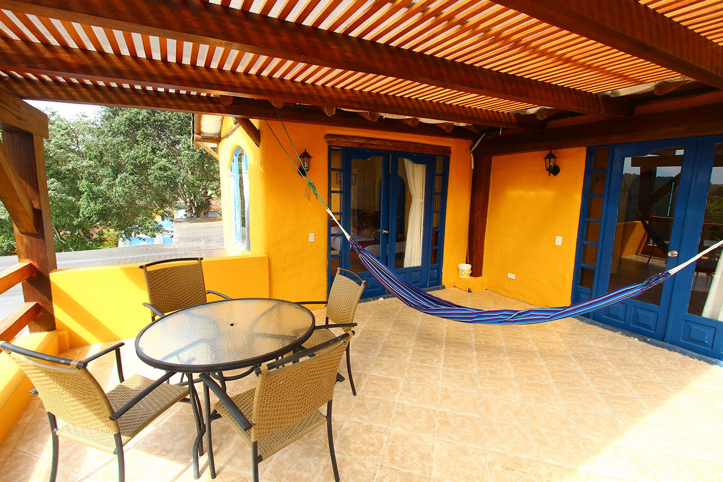 Un patio techado con una mesa y sillas, una hamaca y vistas al exterior.