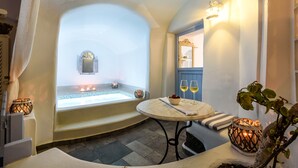Un espacio de spa con una bañera, una mesa con vasos, e iluminación decorativa.