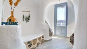 Una habitación con paredes blancas, una puerta azul, una cesta tejida con plantas secas y un letrero que dice 'relax'.
